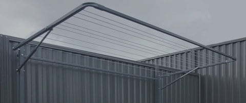 Grey folding clothesline mounted on corrugated fence.